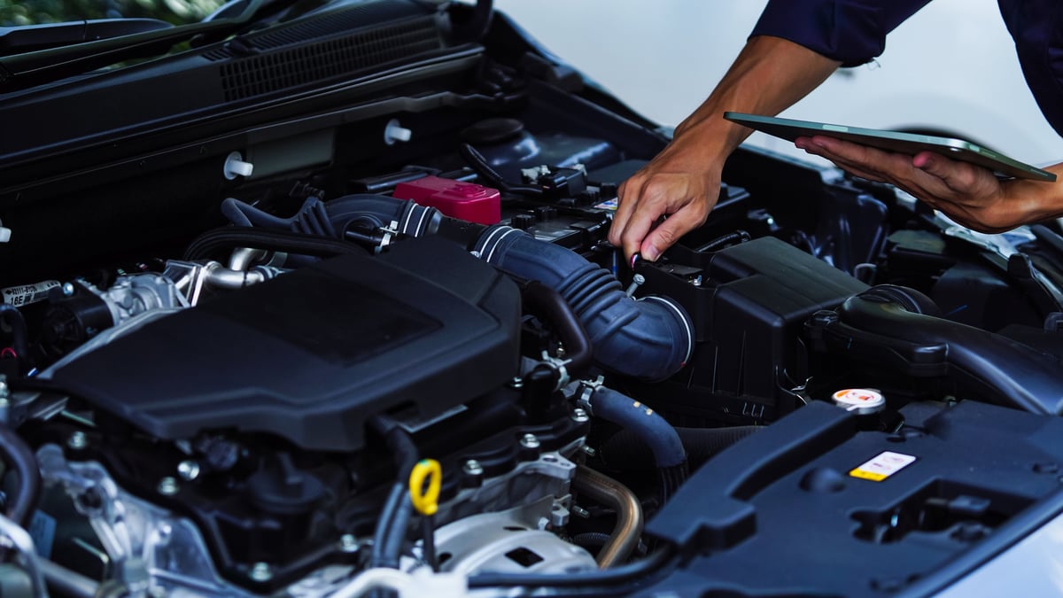 Auto mechanic working on a car engine in a modern garage